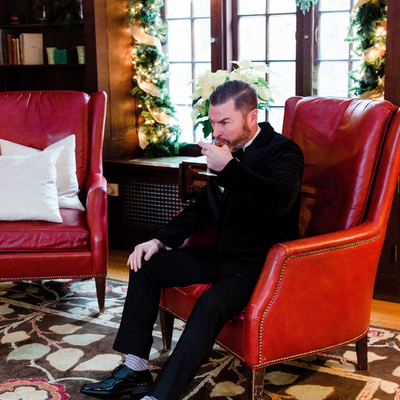 Groom sipping champagne cocktail in library at Willowdale Estate outside Boston, MA