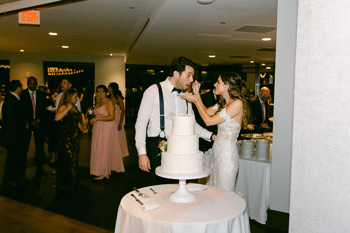 Bride and groom eating and cutting their cake at wedding reception at the State Room