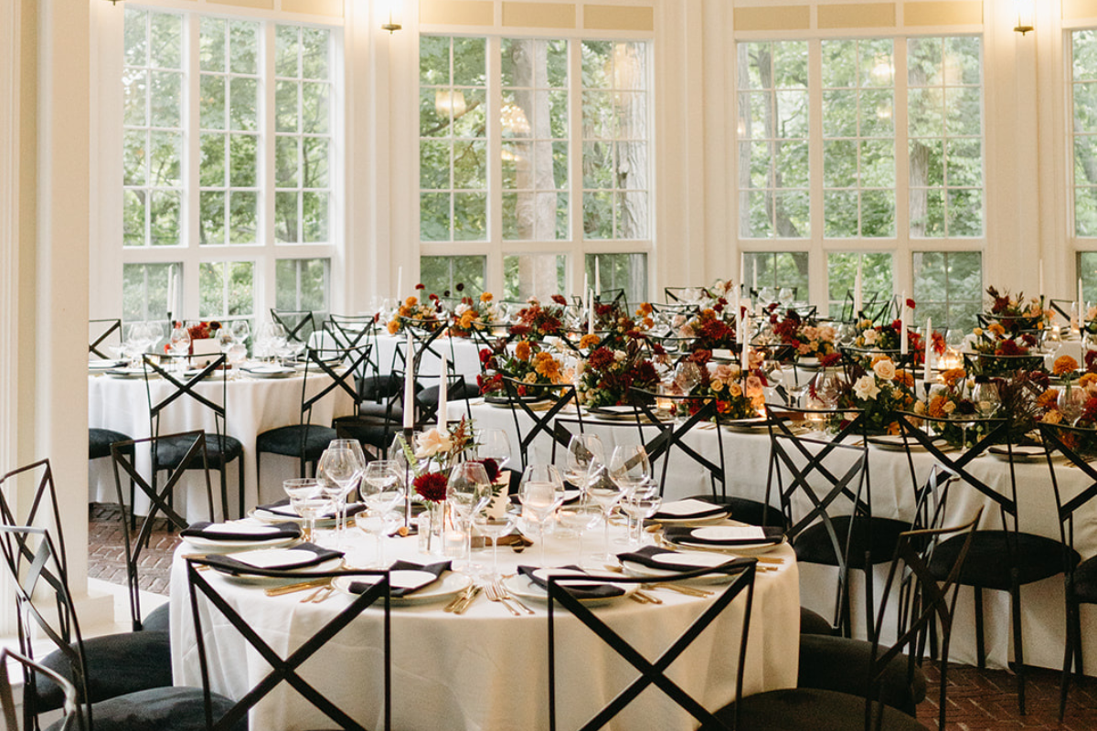 Grand Ballroom at Tupper Manor set for wedding reception with tabletop rentals and a dark and moody floral palette