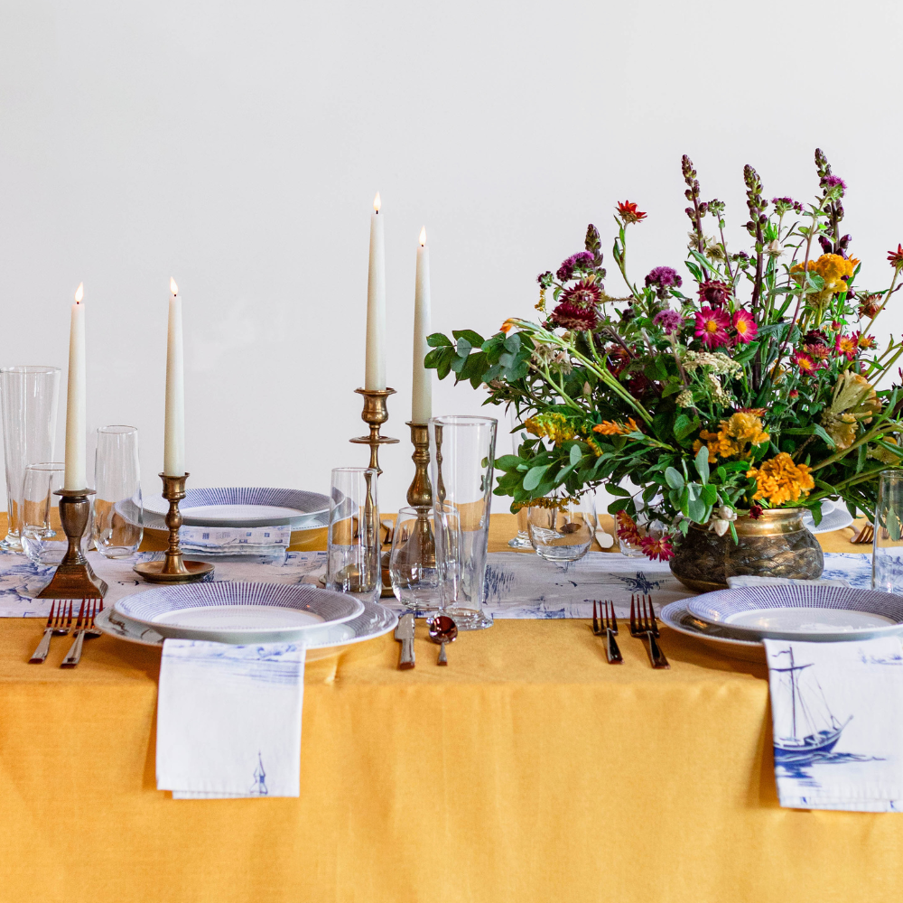 Nautical table setting with brass candlesticks and battery tapers adorn a table in Massachusetts.