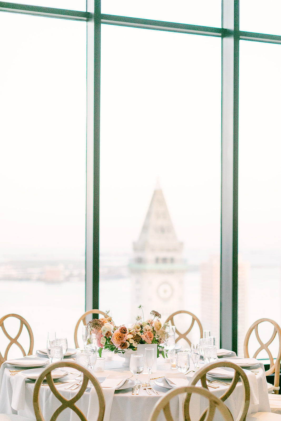 The Boston waterfront view from the State Room venue, Wedding reception with beautiful florals and tabletop set for the party.