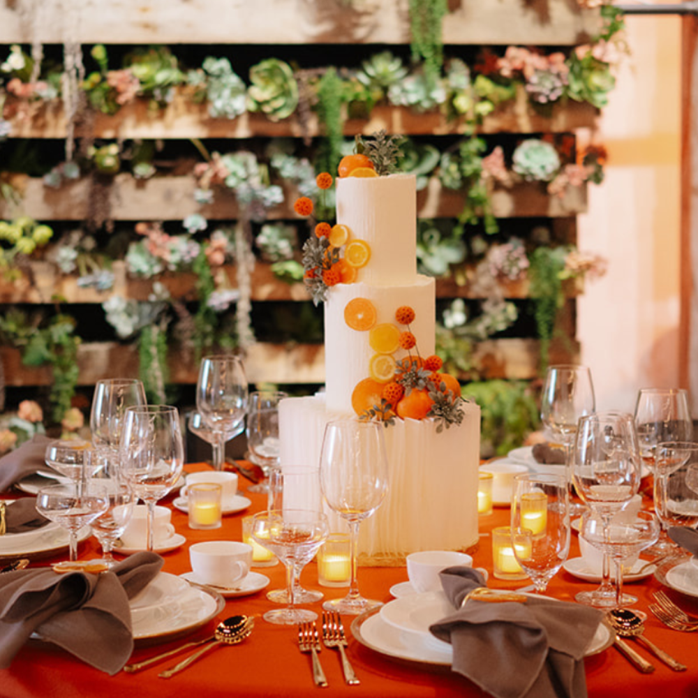 A wedding tablescape with cake as a centerpiece. The Deluxe Glassware is set at the table with other tabletop rentals. Venue of MA.