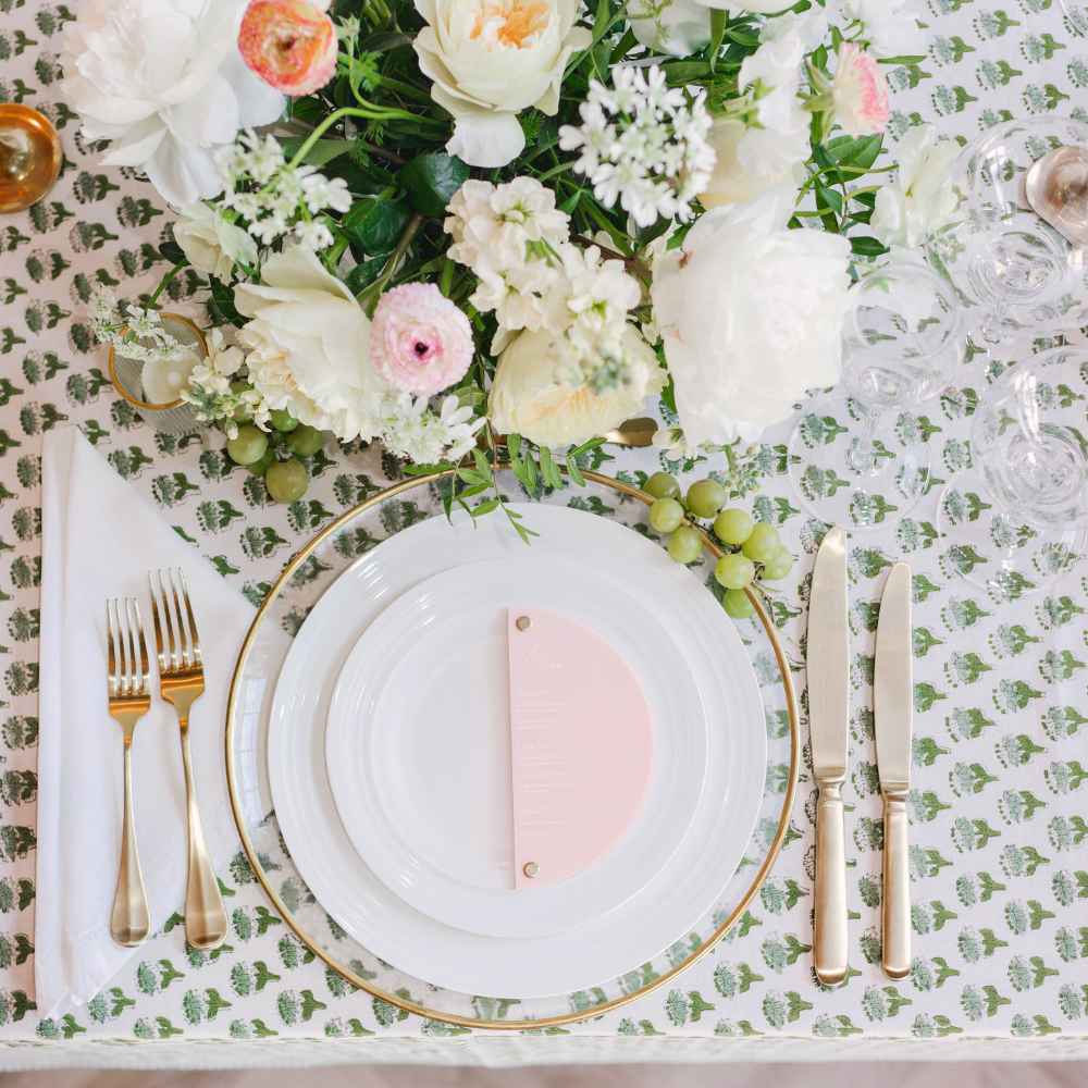 With a gorgeous spring tablescape of heirloom white rimmed plates on a printed tablecloth with pastel flowers at celebration in Massachusetts.