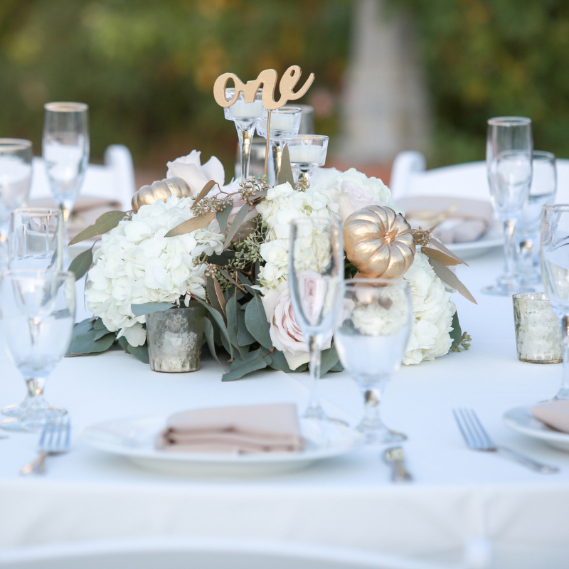 wedding reception table with centerpieces and silver beaded charger set at place setting